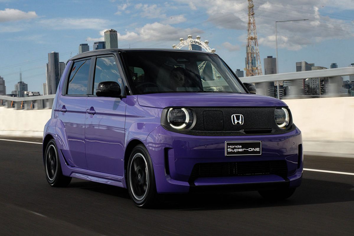 Purple Honda Super-One small boxy EV hatch on arterial road with city skyline in background.
